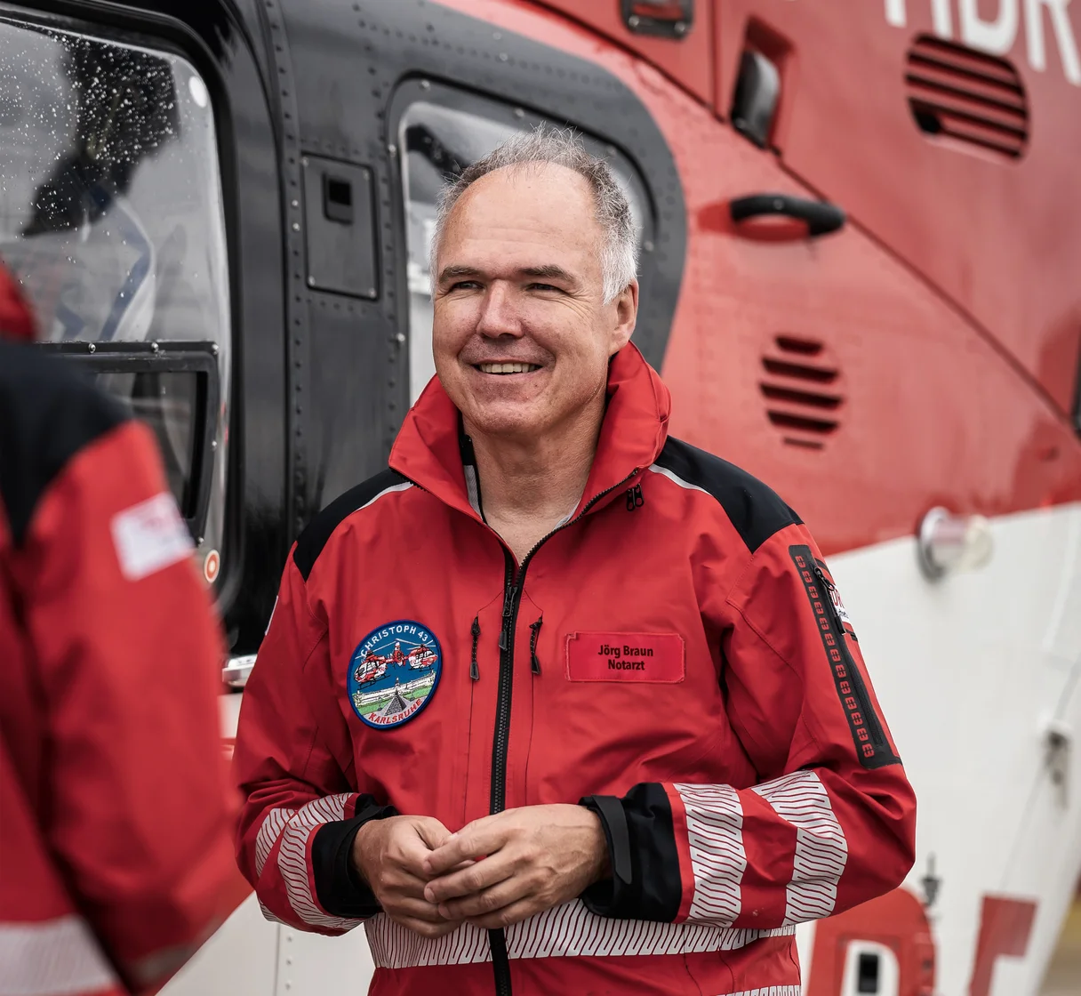 Porträt von Dr. med. Jörg Braun vor einem Rettungshubschrauber der DRF Luftrettung