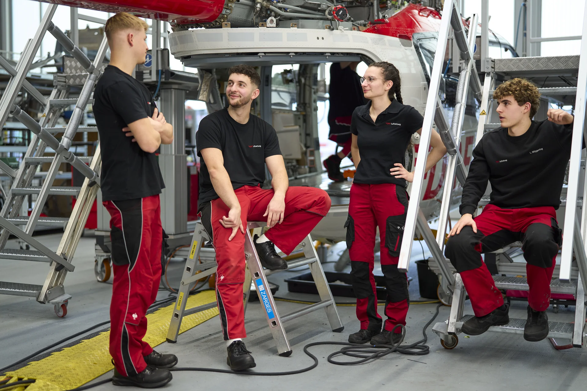 Vier Auszubildende im Bereich Technik der DRF Luftrettung unterhalten sich und stehen in der Werft.