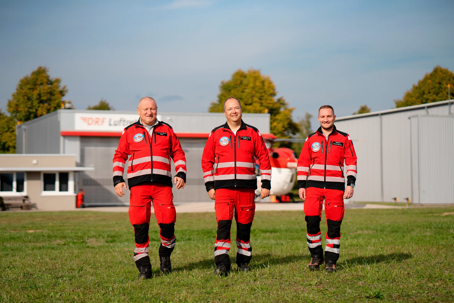 Eine Einsatzcrew läuft gemeinsam vom rot-weißen Rettungshubschrauber weg.