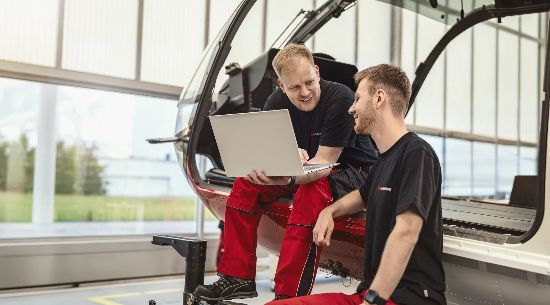 Zwei Techniker der DRF Luftrettung unterhalten sich und schauen dabei auf einen Laptop.