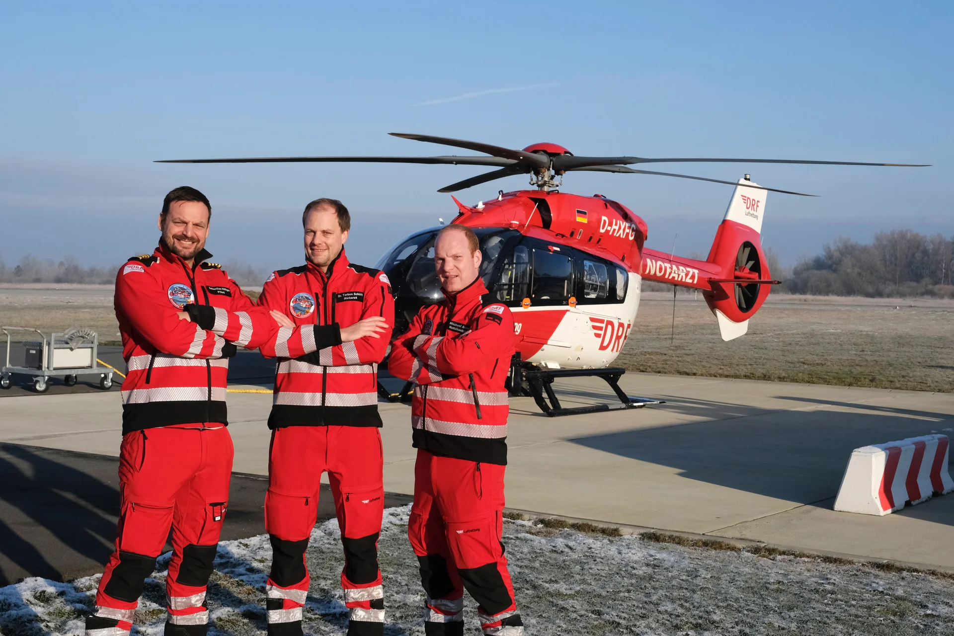 Eine Einsatzcrew steht gemeinsam vor einem rot-weißen Rettungshubschrauber.