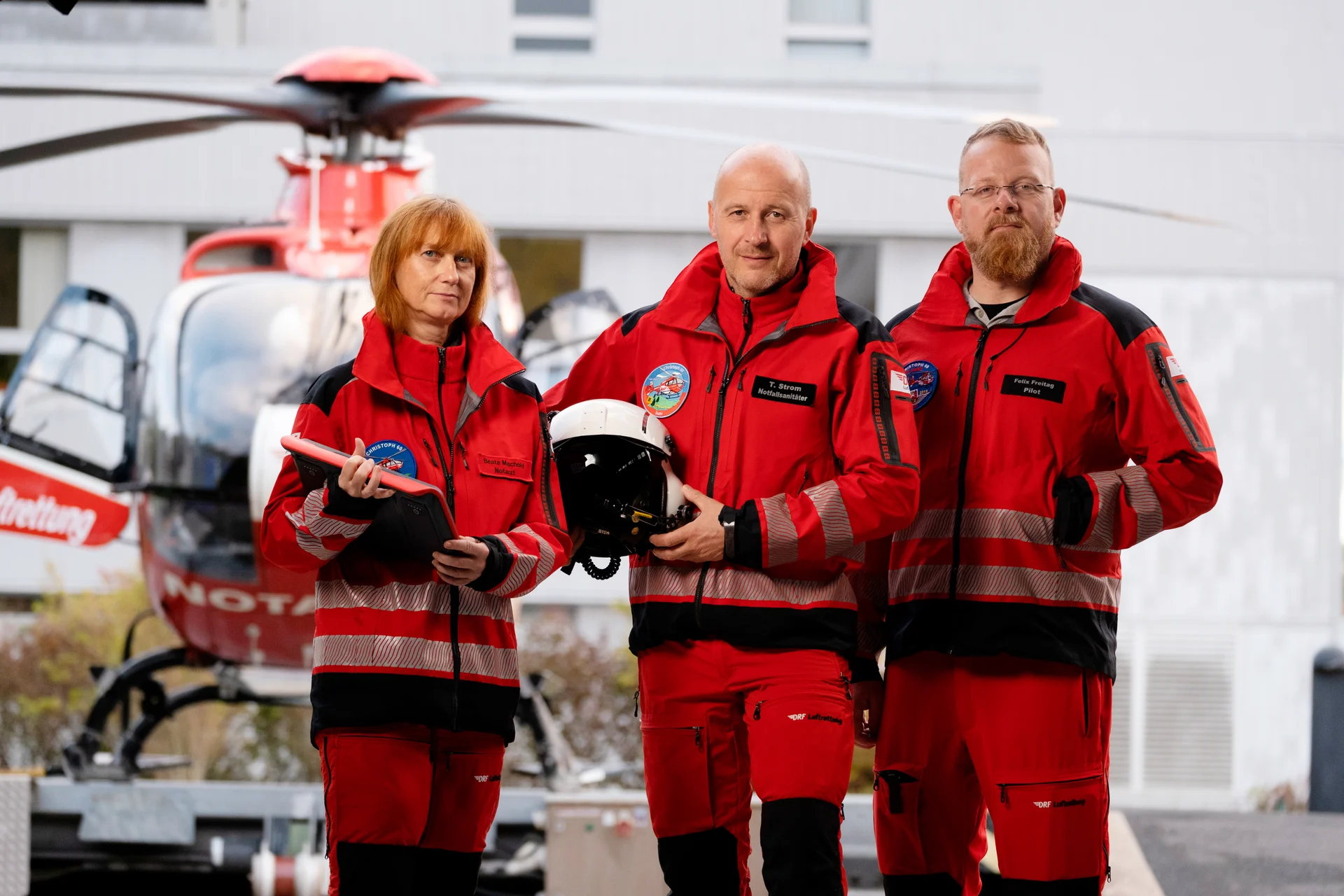 Ein rot-weißer Rettungshubschrauber steht vor dem Hangar.