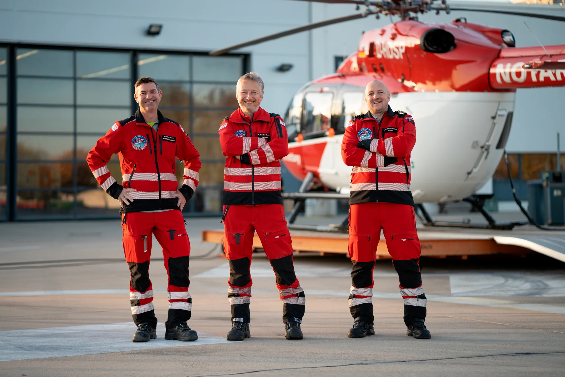 Eine Einsatzcrew steht gemeinsam vor einem rot-weißen Rettungshubschrauber.