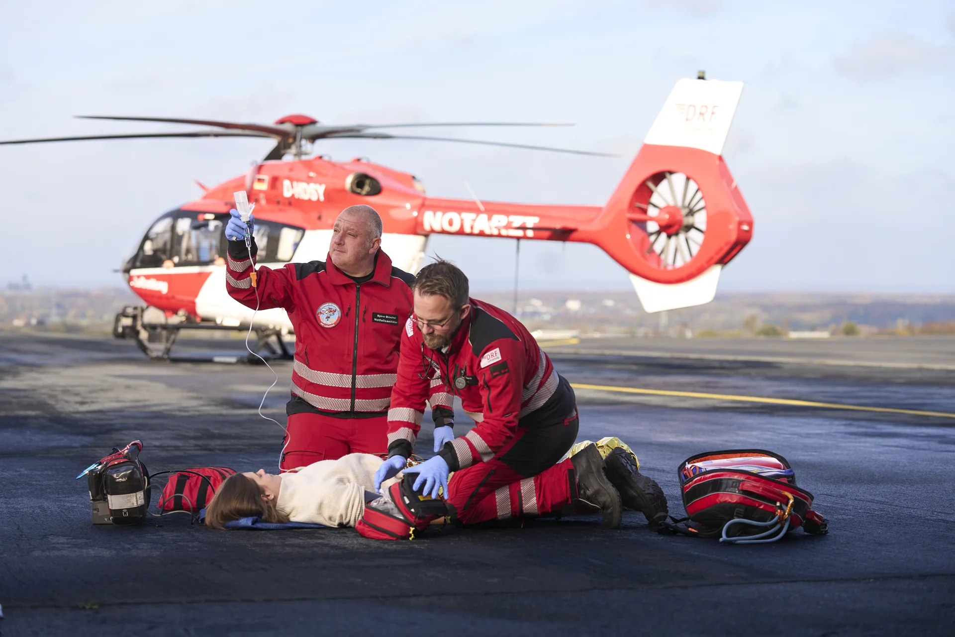 Notfallmedizinische Versorgung eines Patienten durch die Crew der DRF Luftrettung vor einem Rettungshubschrauber