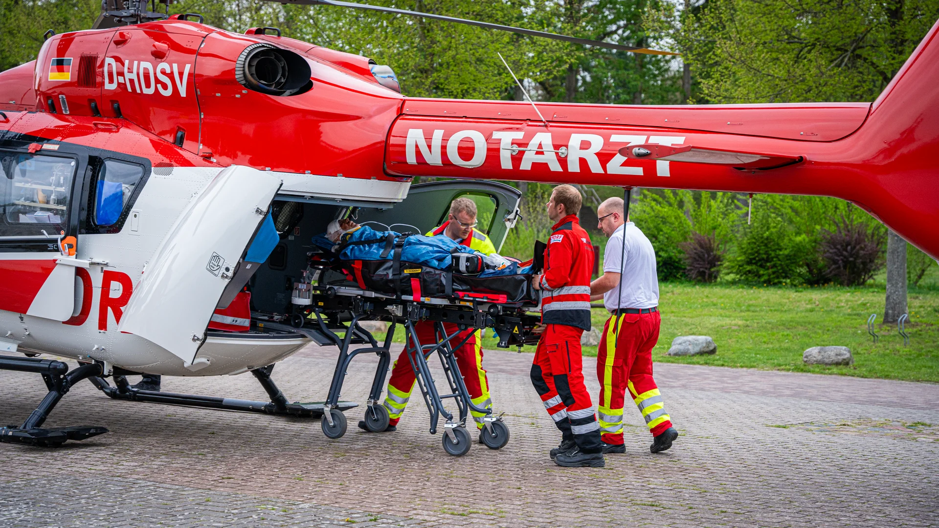 Patient wird von der Crew der DRF Luftrettung in einen Rettungshubschrauber transportiert