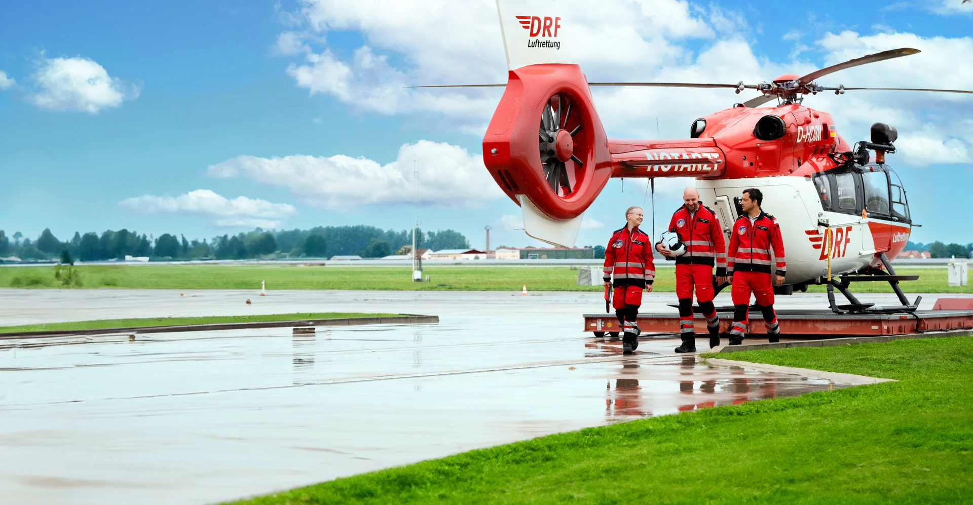 Eine Einsatzcrew läuft gemeinsam vom rot-weißen Rettungshubschrauber weg.